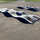 Custom pump track (skateboard ramp) on a concrete slab at a public park.