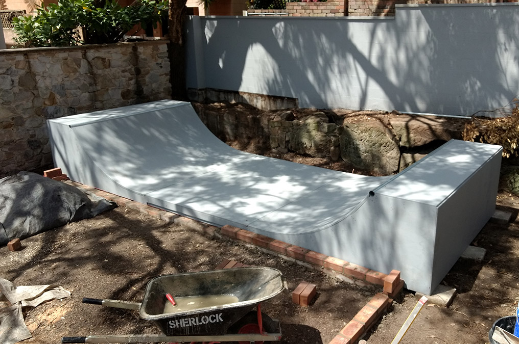 2.5ft high mini ramp - (half pipe skateboard ramp), painted grey with custom landscaping.
